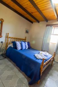 a bedroom with a bed with blue sheets and a window at Pousada Estrela da Serra in Monte Verde