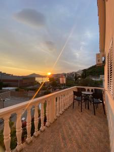 a balcony with a table and chairs and the sunset at Apartmani Kažanegra33 in Pržno