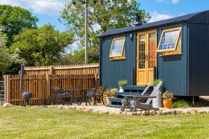 a green tiny house with a table and chairs at The Hut at Pengelli in Nelson