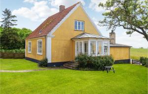 a small yellow house with a grass yard at Beautiful Home In Fem With Wifi in Maribo