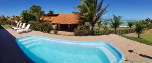 una piscina azul frente a una casa en Casa espetacular em condomínio pé-na-areia, PZ11, en Rio do Fogo