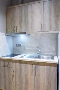 una cocina con fregadero y armarios de madera en NikoleTakis Apartments en Paralia Panteleimonos