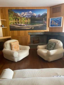 a living room with two white chairs and a large painting at Belvedere da Cesarina in Tarvisio