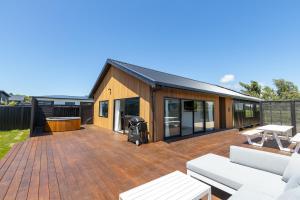 ein Haus mit einer Holzterrasse mit einem Grill in der Unterkunft The Green House - Luxury Eco Escape in Martinborough 