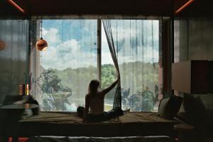 a woman sitting on a bed looking out of a window at Mix Brussels --Gym & Wellness for adults only-- in Brussels