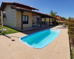 a large blue swimming pool in front of a house at Casa espetacular em condomínio pé-na-areia, PZ11 in Rio do Fogo