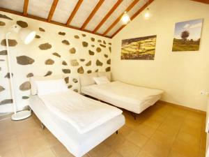 2 camas en una habitación con una pared con rocas en El Pirguan Holiday House, your oasis in La Gomera, en Vallehermoso