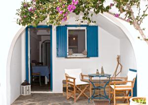 um pátio com uma porta azul, cadeiras e uma mesa em Porto Kalma em Agios Ioannis