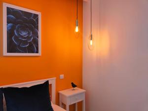 a bedroom with an orange wall with a bed and two lights at Blue Essence Apartment - Central in Coimbra