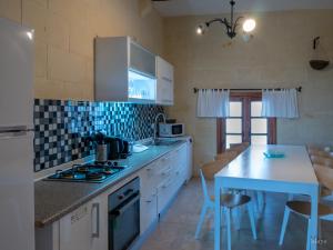 a kitchen with white cabinets and a table and a counter at VinDor Villa in Sannat