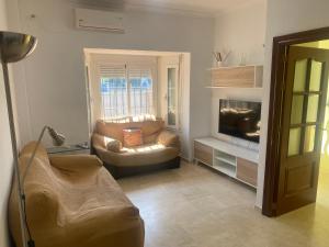 een woonkamer met een bank en een televisie bij Casa hasta 6 personas in Carraca