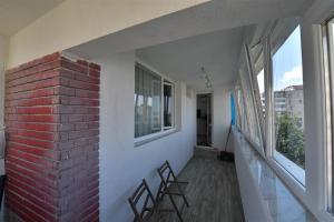 Habitación con 2 sillas, pared de ladrillo y ventanas en Apartament de lux Moghioros Park, en Bucarest