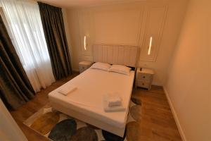 Un pequeño dormitorio con una cama blanca y una ventana en Apartament de lux Moghioros Park, en Bucarest