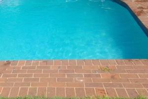 a blue swimming pool with a brick floor and blue water at Cottage near Lagoon beach in Durban in Durban