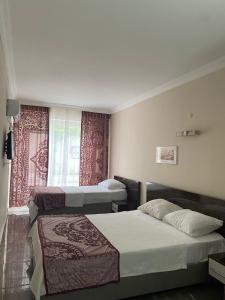 um quarto de hotel com duas camas e uma janela em ÇAMLIK PANSİYON em Antalya