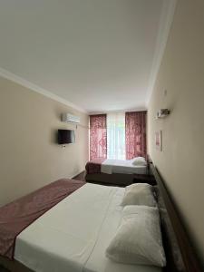 two beds in a small room with a window at ÇAMLIK PANSİYON in Antalya