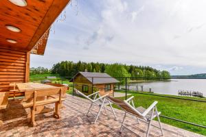 eine Terrasse mit Stühlen, einem Tisch und einem Haus in der Unterkunft Nijolės sodyba in Aukštadvaris