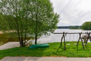 a green canoe on the grass next to a lake at Nijolės sodyba in Aukštadvaris