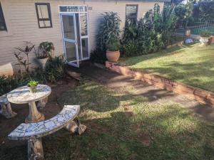 a backyard with a table and benches in the grass at Cottage near Lagoon beach in Durban in Durban