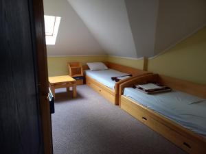 Habitación pequeña con 2 camas y silla en Garni Hotel Lupus en Kanjiža
