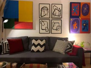 uma sala de estar com um sofá cinzento e algumas fotografias em Excelente departamento en la Condesa em Cidade do México