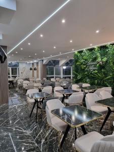 a restaurant with tables and chairs and plants at Hôtel Restaurant Le Relais - Pau Nord in Lons