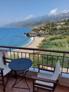 balcón con mesa y sillas y playa en Anarrousa Studios & Apartments, en Evdilos