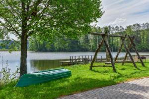 a green canoe on the grass next to a lake at Nijolės sodyba in Aukštadvaris
