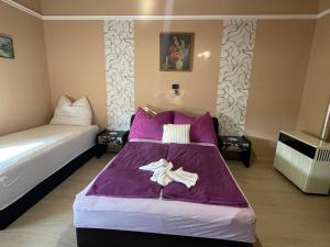1 Schlafzimmer mit 2 Betten und lila Bettwäsche in der Unterkunft Ravasz Apartman in Balatonboglár
