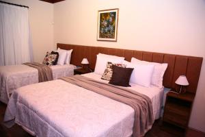 um quarto com 2 camas e almofadas em Pousada Miraflores em Campos do Jordão