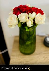 un vase vert rempli de roses rouges et blanches dans l'établissement Apartament Lux Crialy - self check-in, à Timişoara