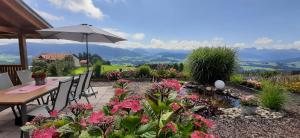 een patio met een tafel met een parasol en bloemen bij Antoniushof in Sulzberg