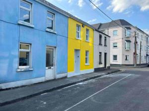 a row of colorful buildings on an empty street at “The Art House 6” Galway, Woodquay in Galway