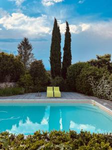 a swimming pool in a garden with two yellow chairs at Chambres de charme avec jardin et piscine in Coulonges-sur-lʼAutize