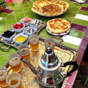uma mesa com uma chaleira de chá, pizza e bebidas em Appartement calme, Guéliz em Marrakech