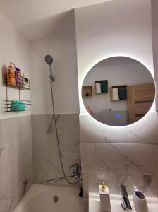 y baño con bañera y espejo redondo. en Christal Apartment, en Bacău 7 fotos más