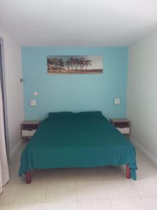 a bedroom with a green bed with two night stands at West Indies in Caritan