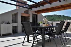 a black dining table and chairs on a patio at SOL luxury residence near the beach with shared heated pool in Božava