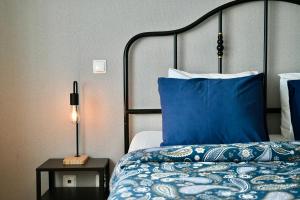 a bed with blue pillows and a lamp on a table at Porto Cozy House in Porto