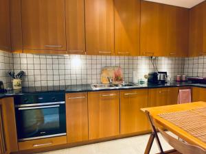- une cuisine avec des placards en bois, une cuisinière et une table dans l'établissement Athens Riviera Garden Views Apartment, à Athènes
