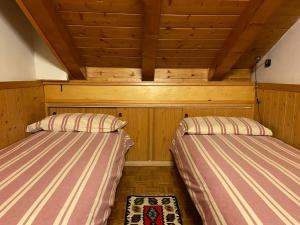 two beds in a room with wooden walls and ceilings at Appartamento Fronte Piste in Auronzo di Cadore