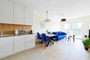 a kitchen and dining room with a table and blue chairs at Apartament Marinus ProstyWynajem Gdańsk Brzeźno in Gdańsk