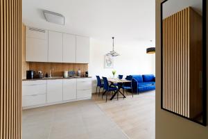 a kitchen with white cabinets and a table with blue chairs at Apartament Marinus ProstyWynajem Gdańsk Brzeźno in Gdańsk +7 photos