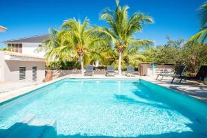 a swimming pool with palm trees and a house at Villa Bon Bon - Jan Thiel - Vista Royal in Jan Thiel
