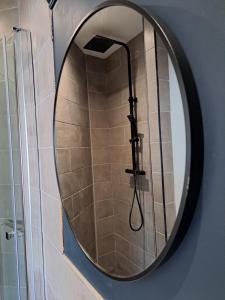 a round mirror with a shower in a bathroom at Kingsdown Apartment in Great Malvern +19 photos
