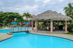 a resort with a swimming pool with a thatch roof at Ocean Dream Art Deco Studio w/balcony in Cabarete