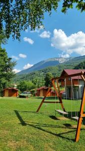 eine Schaukel auf einem Feld mit einem Haus in der Unterkunft Ethno Village Koljeno Camp & Bungalows in Andrijevica