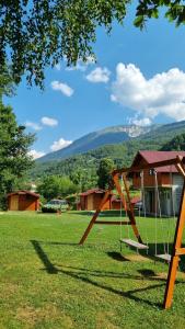 a swing set in a field with a house at Ethno Village Koljeno Camp & Bungalows in Andrijevica