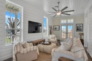 a living room with white furniture and a flat screen tv at Luxury townhome, steps to beach and resort fun! in Port Aransas