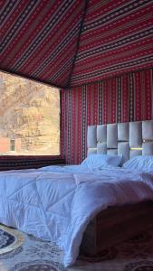 a bedroom with a large bed with a red wall at Adam Bedouin camp in Wadi Rum